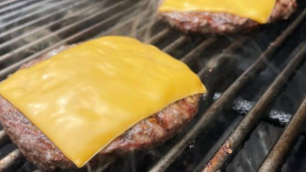 Grilling burgers with cheese melting as they're almost done.