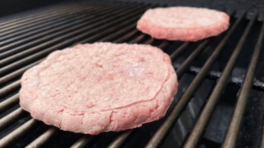 How to grill frozen burgers, starting with a frozen patty placed on a hot grill.