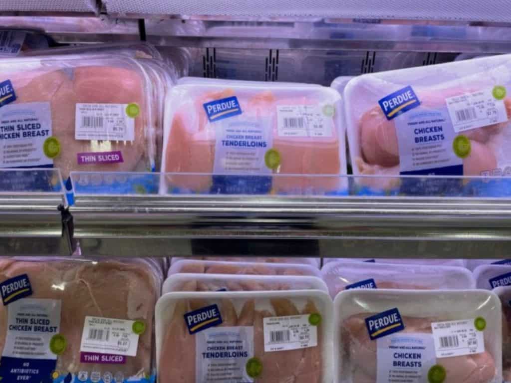 Supermarket shelf showing stacks of chicken cutlets, chicken breast, and chicken tenders.