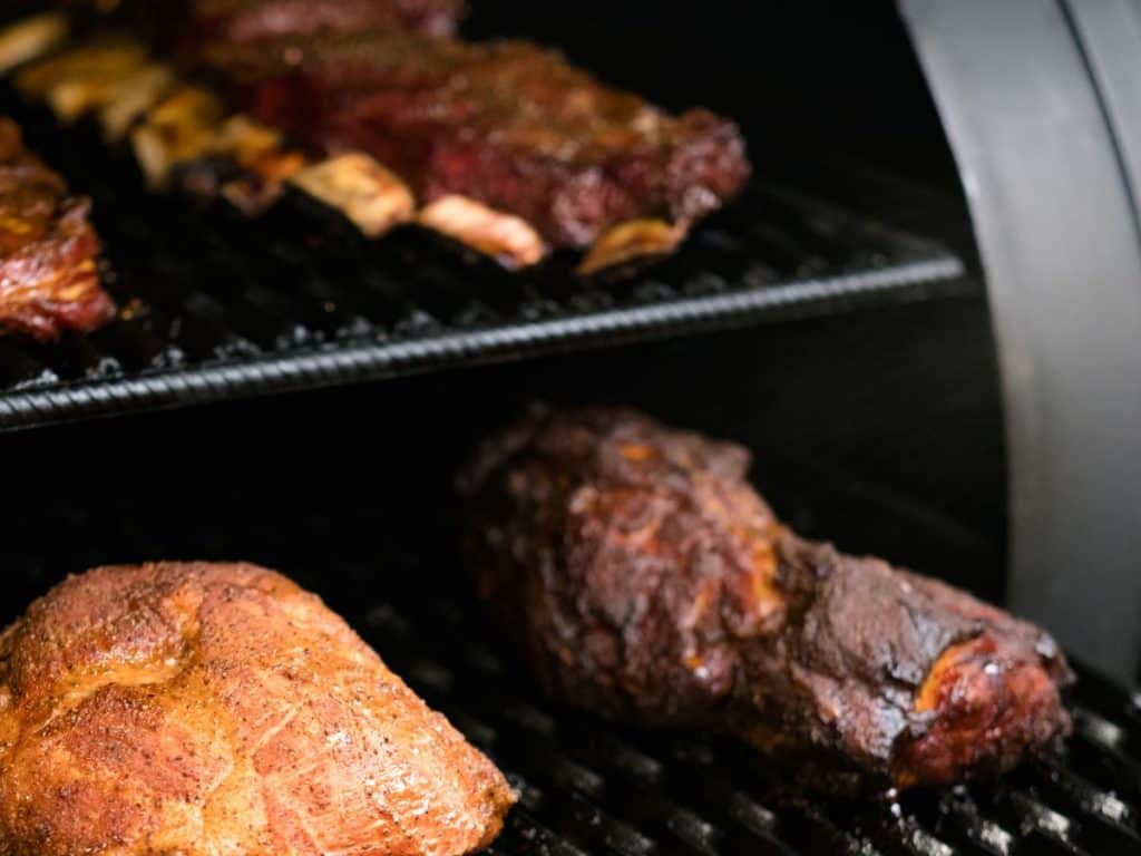 A rack of ribs and pork slowly smoking on one of the best smokers for beginners.