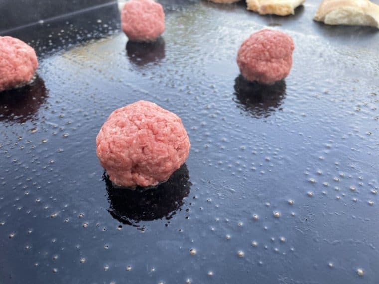 Balls of ground beef on the Blackstone griddle before they are pressed into smash burgers.