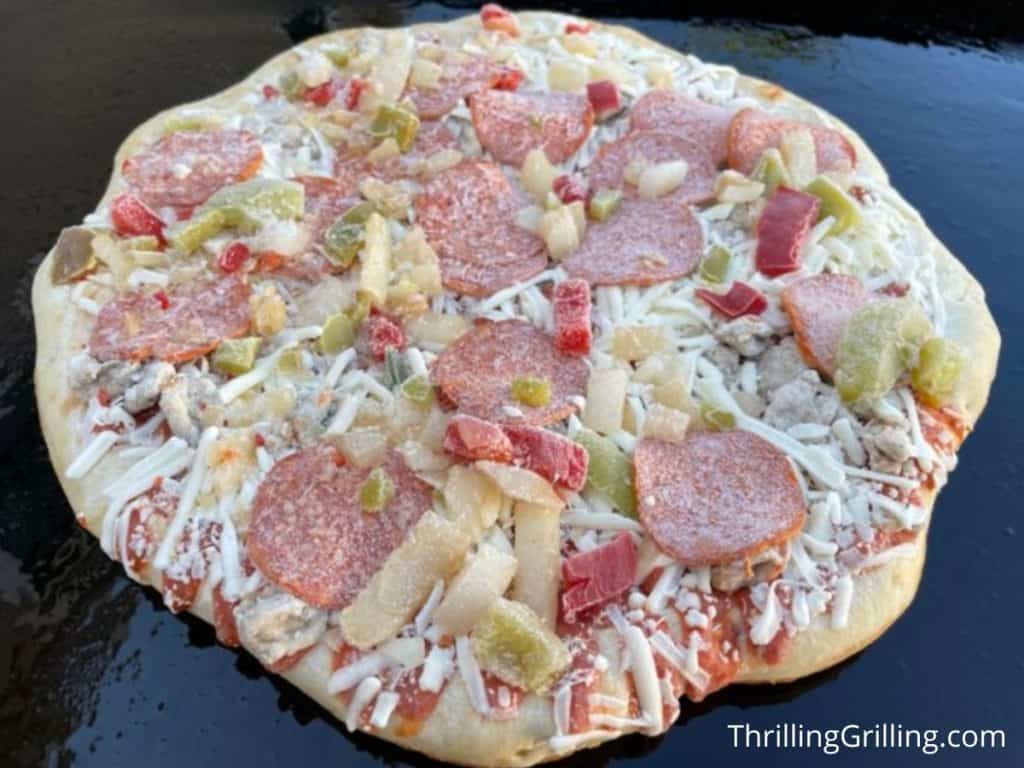 Frozen Digiorno Supreme pizza cooking on a Blackstone griddle
