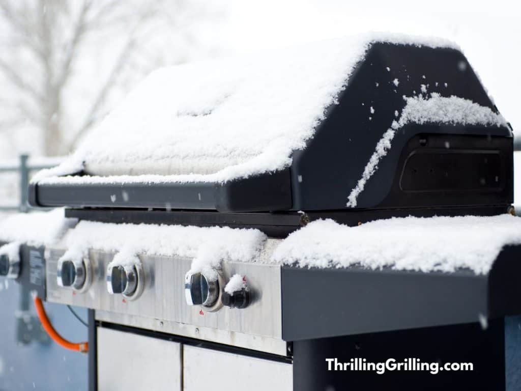 A gas grill covered in snow but ready for some winter grilling