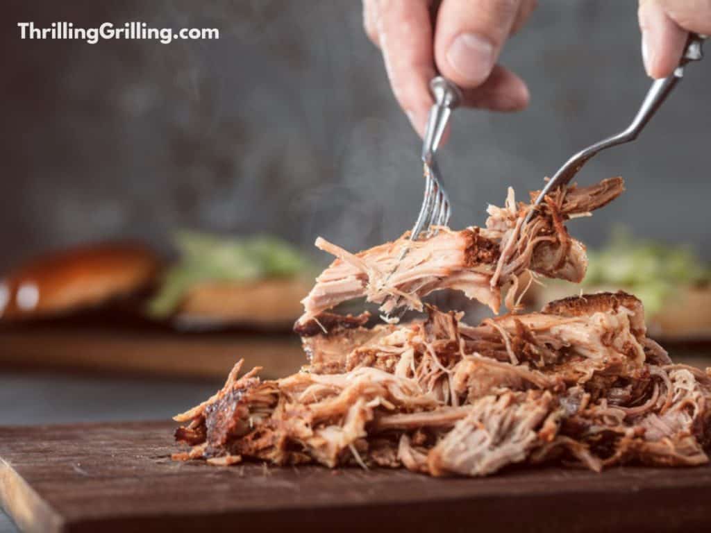 Demonstrating how to shred pulled pork with two forks.